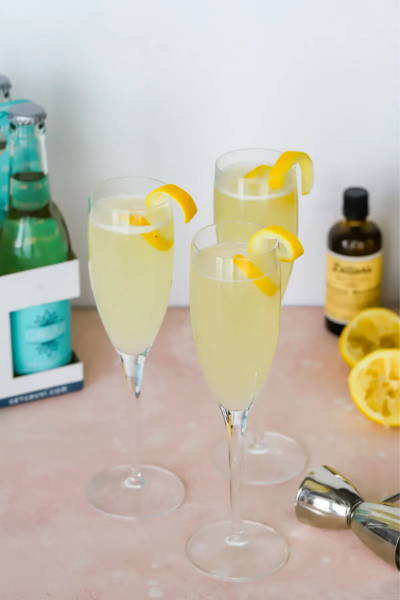 Three champagne flutes filled with non alcoholic french 75 and each topped with a lemon twist.