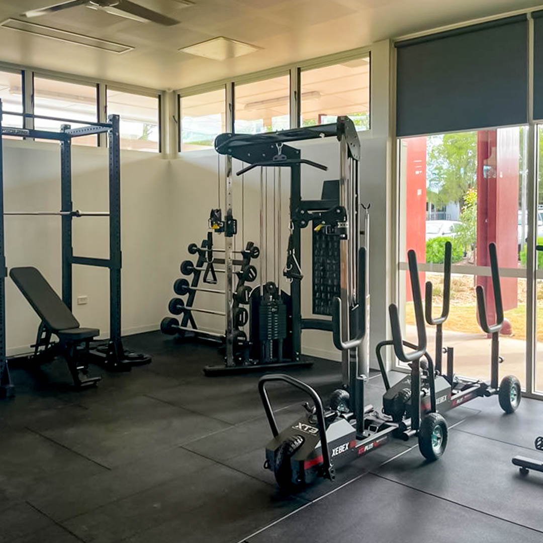 A comprehensive overview of a high school gym fit-out, showcasing a fully equipped space with power racks, bikes, sleds, ski trainers, and plyo boxes, designed to cater to every aspect of student fitness training.