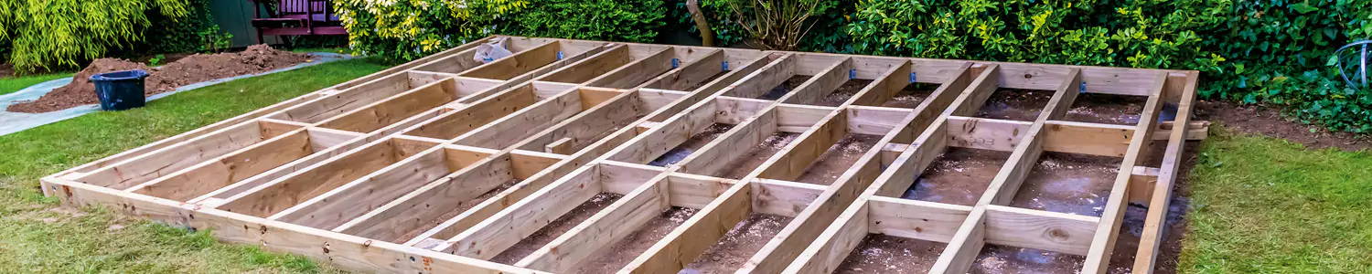 An image of a decking joist being placed on someone's garden to act as a foundation for decking to go on top of it.
