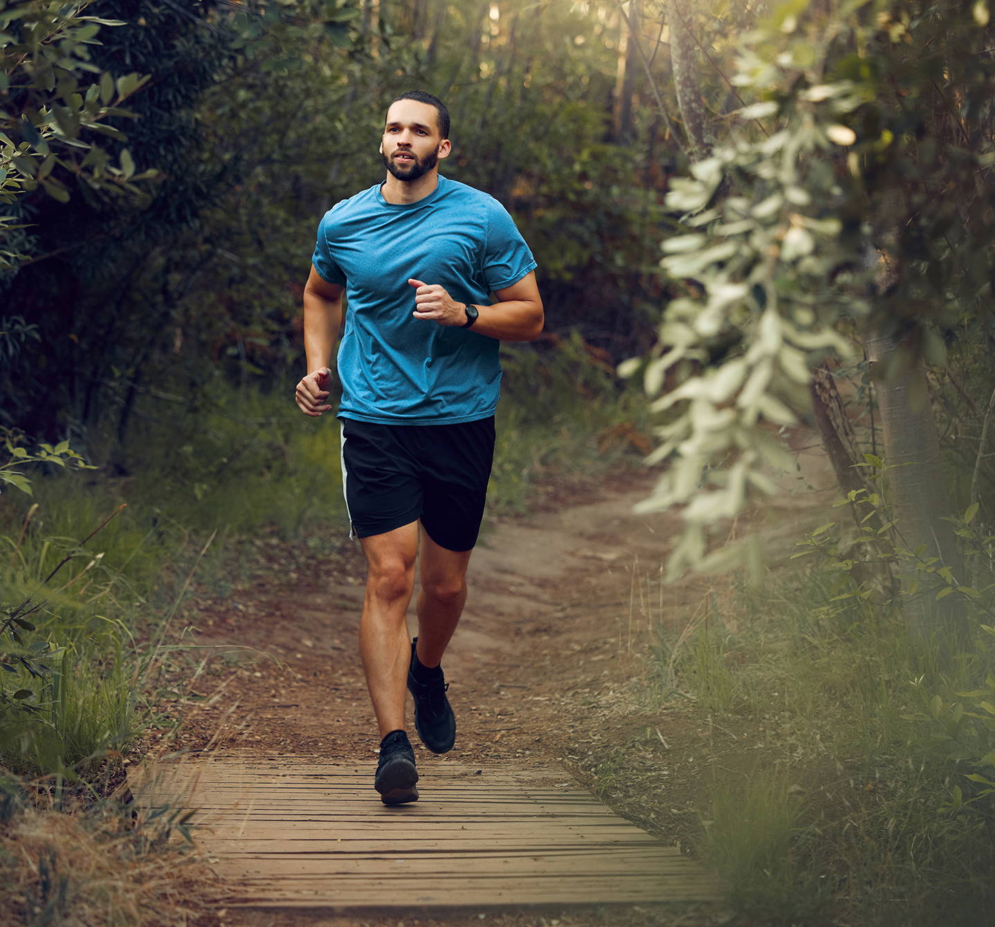 Ein Mann mit Heuschnupfen joggt in kurzer Sporthose und T-Shirt am Wochenende durch den Wald, dafür muss er seine Heuschnupfenbeschwerden im Griff haben.
