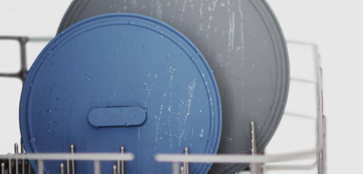 Blue and Grey Misen Universal LIds in a dishwasher rack, still damp from a rinse cycle.
