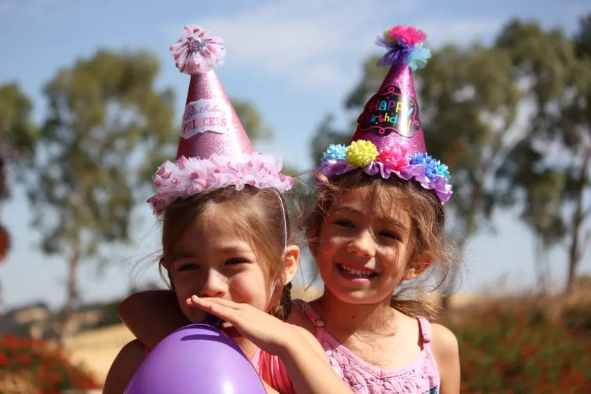 Image of two girls wearing colorful party hats.