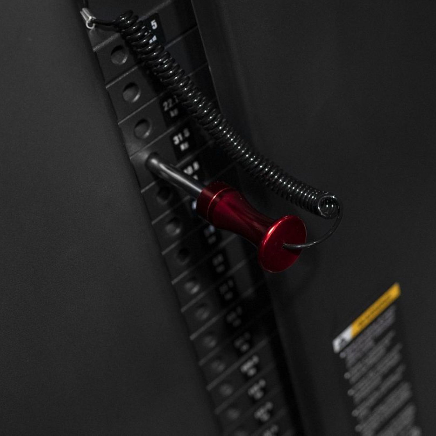 Red tool attached to a black panel with a coiled wire.