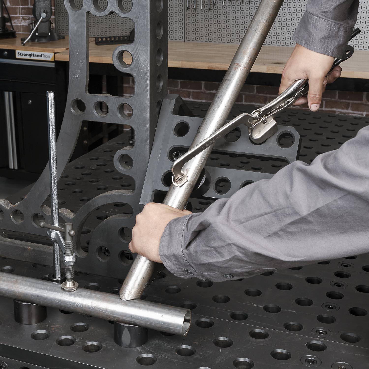 Person using a tool on a metal work surface with holes.