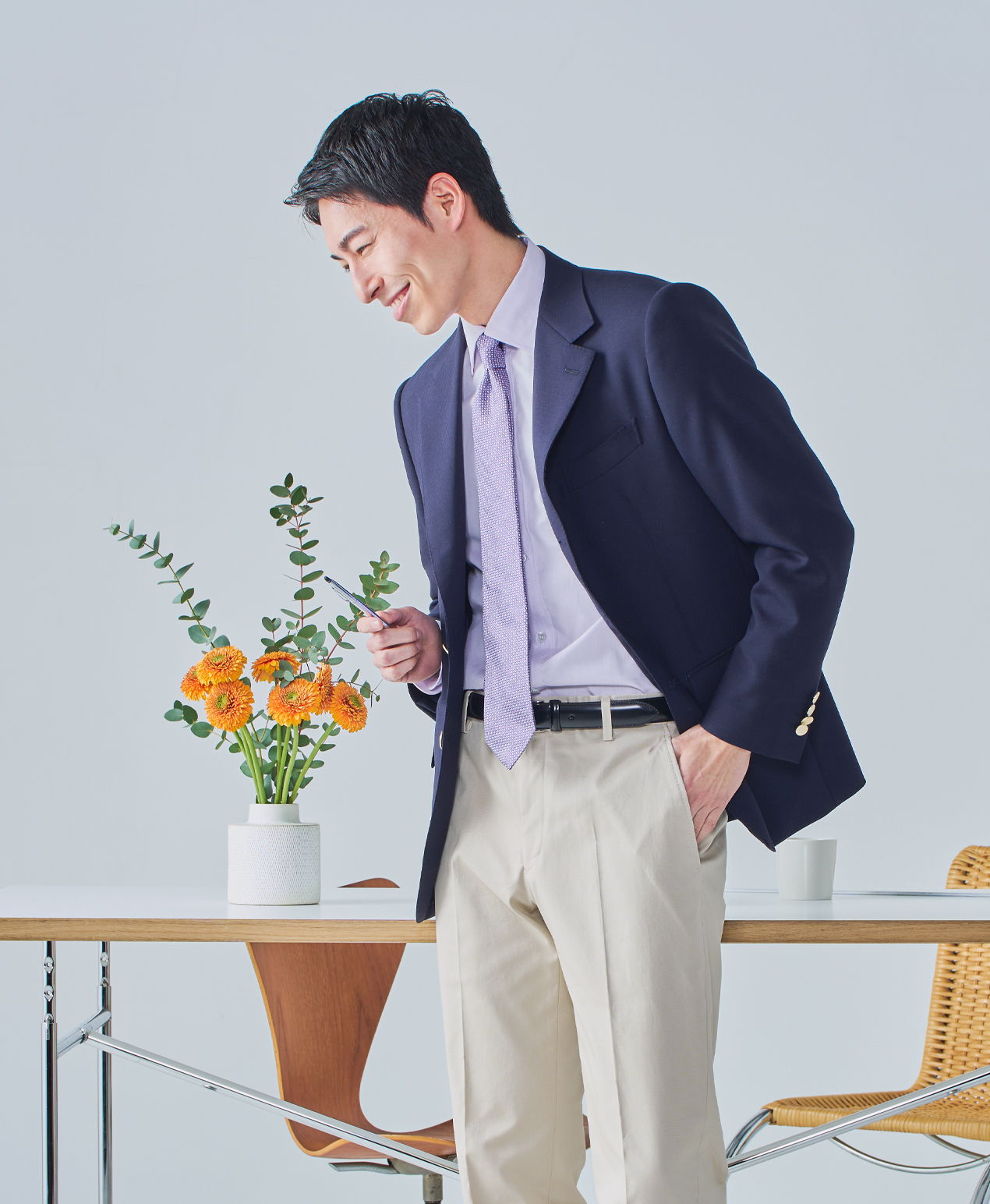 Man in a suit smiling beside a flower arrangement on a table.