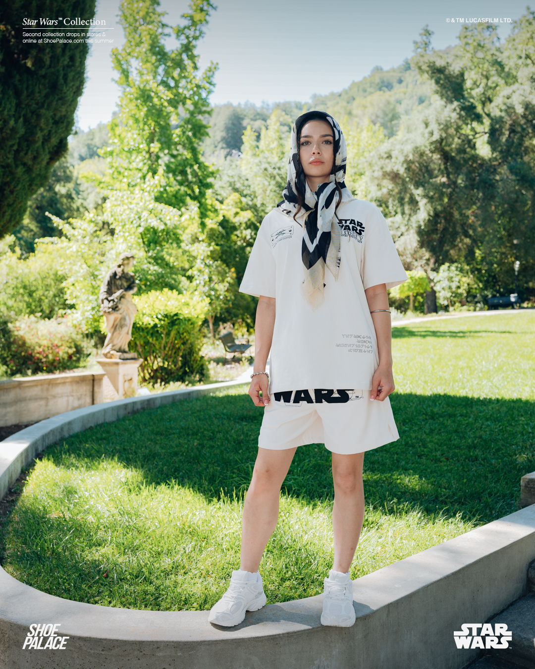 Person wearing a white outfit and scarf, standing on green grass.
