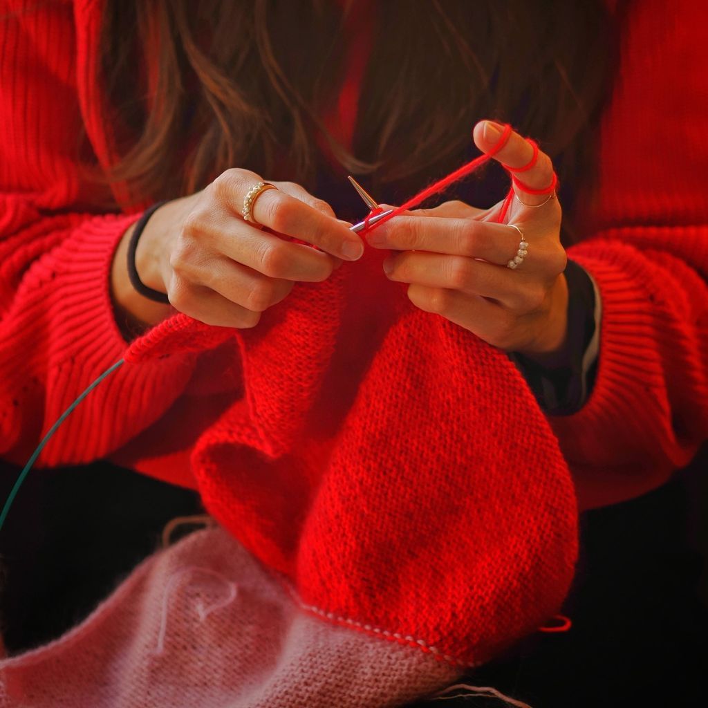 Person die gerade ein Tuch strickt.