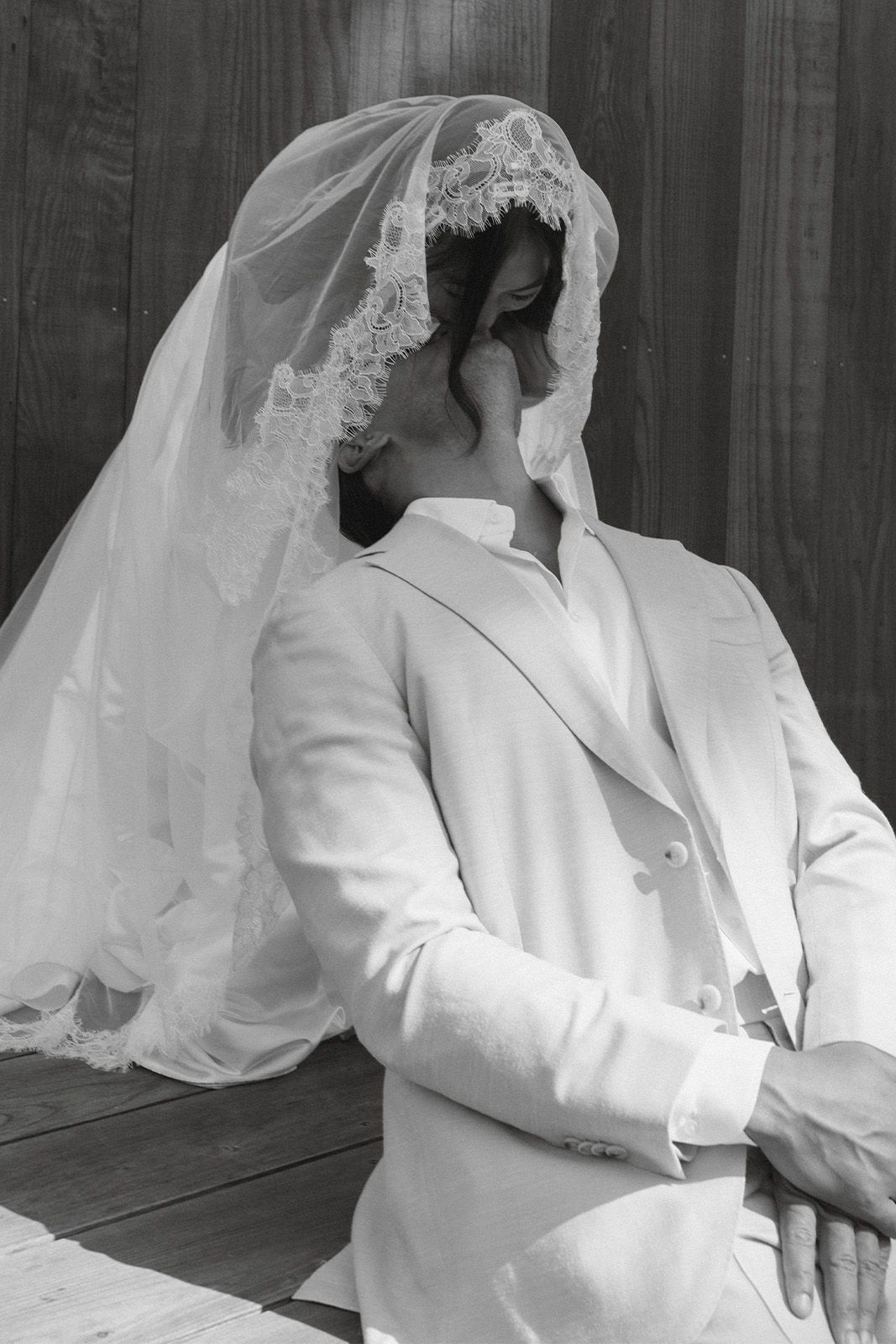 Person in a wedding dress and suit, seated, with a whimsical pose.