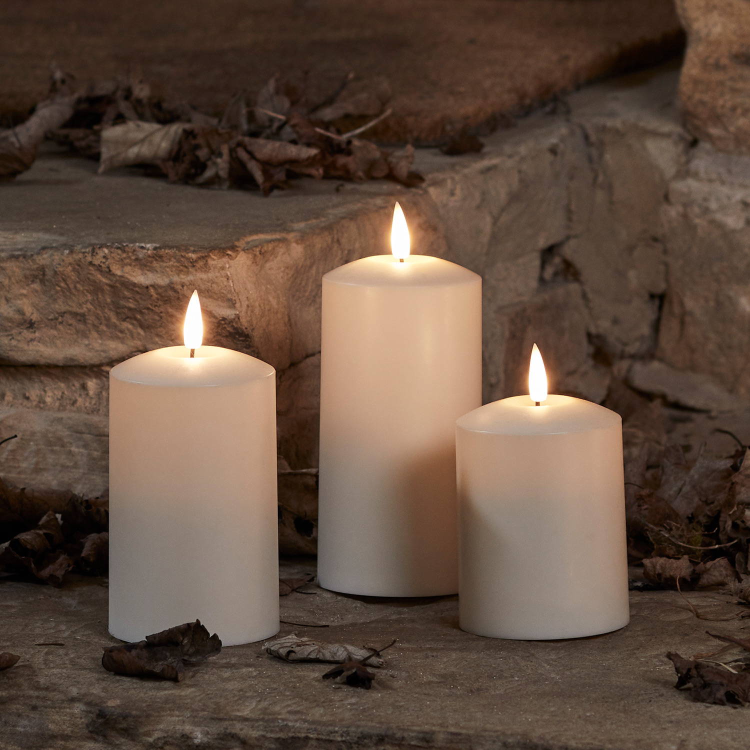 3 ivory autumn candles outdoors on a porch.