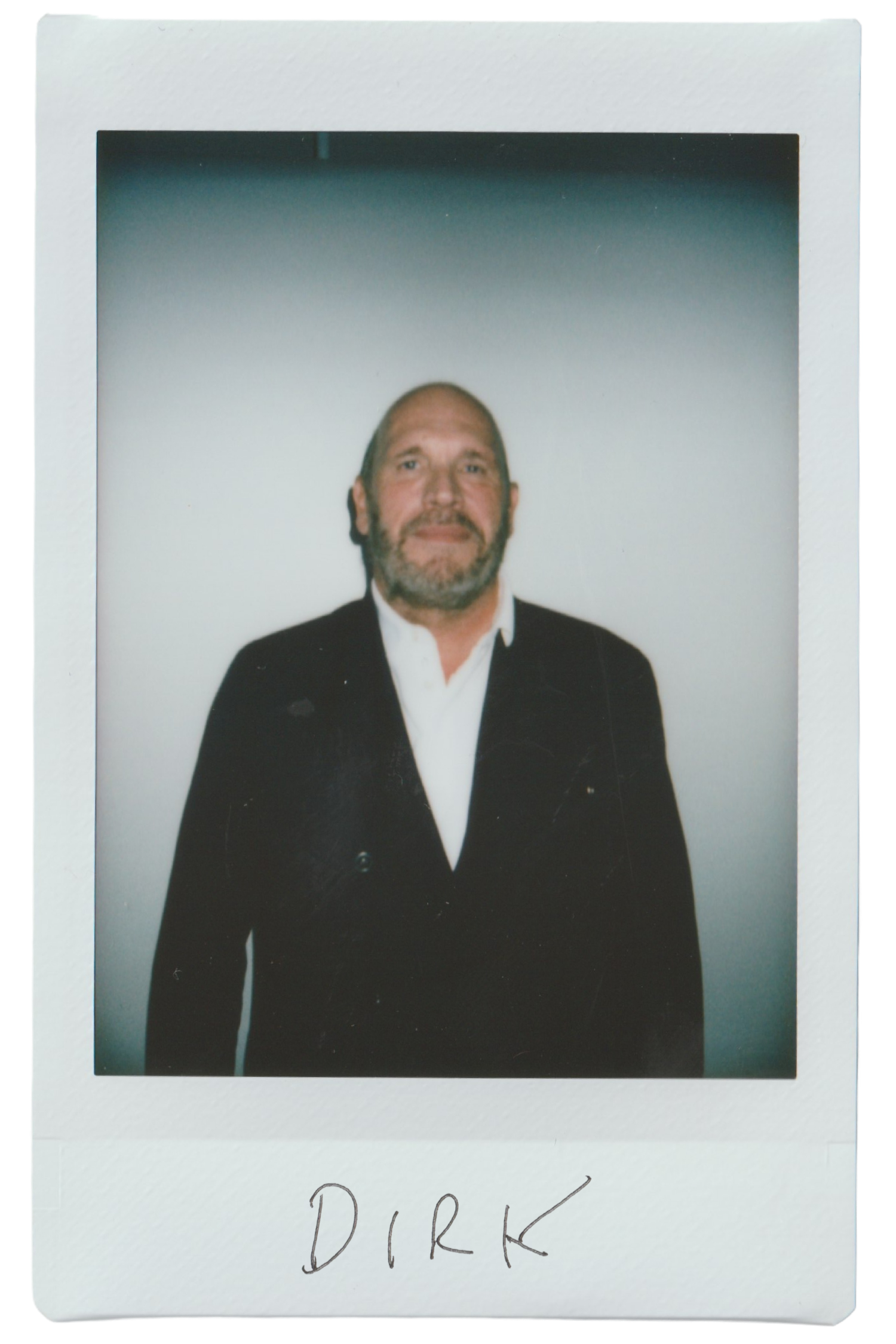 A man in a suit standing against a plain background, labeled 