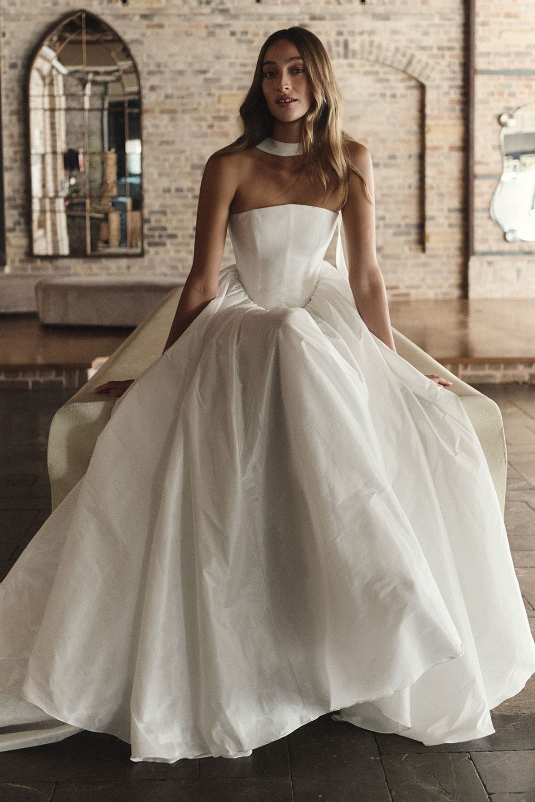 A woman in a strapless white gown sitting in an elegant setting.