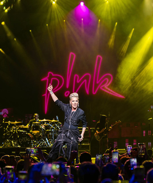 Singer performing on stage with vibrant lighting and crowd visibility.
