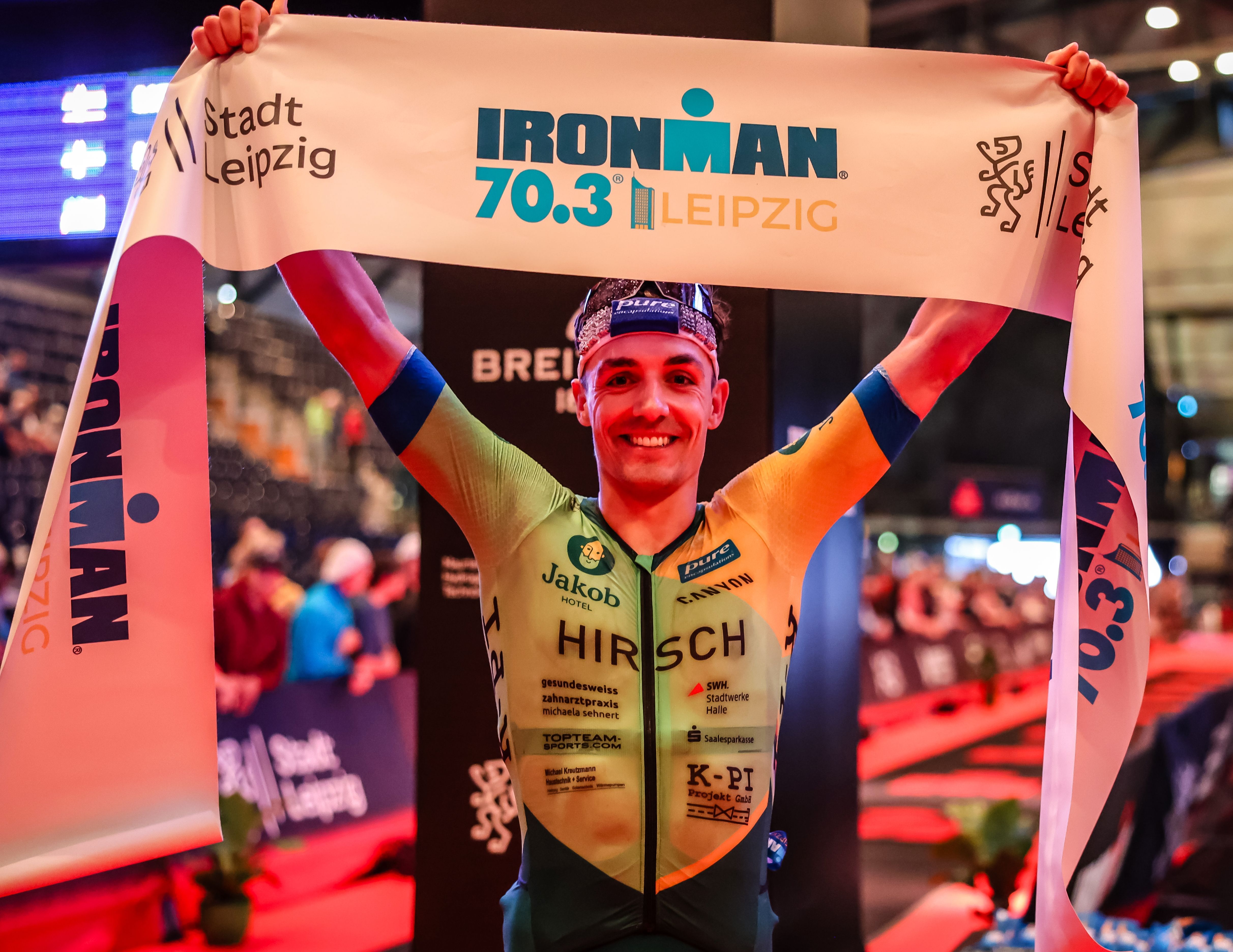 Wilhelm Hirsch strahlt nach seinem Sieg beim Ironman 70.3 Leipzig in die Kamera.