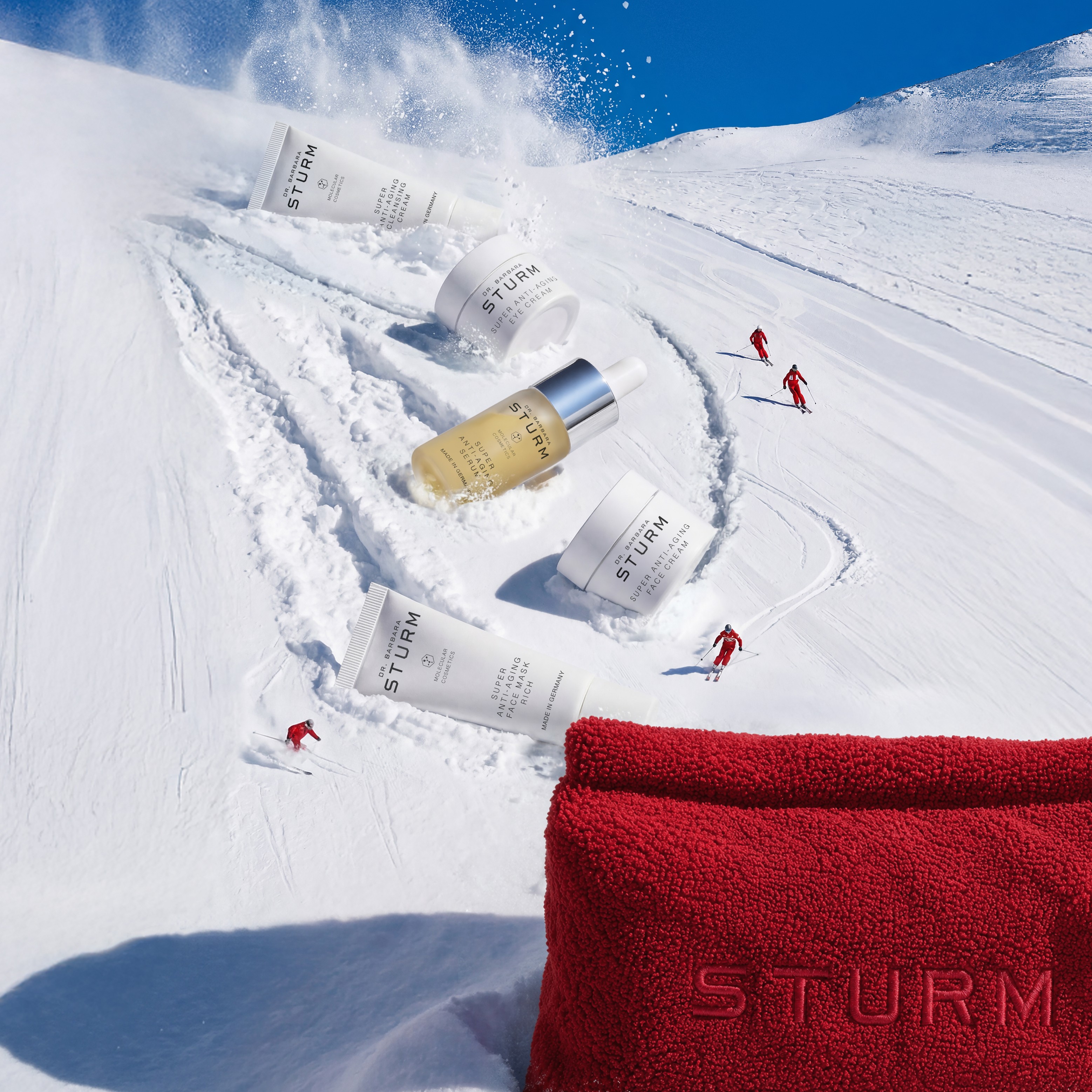 Skiers on snowy slope with skincare products and red bag in foreground.