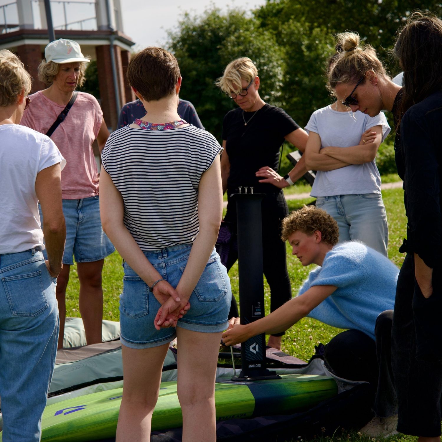 Group of people gathered around, observing a demonstration on a kayak.
