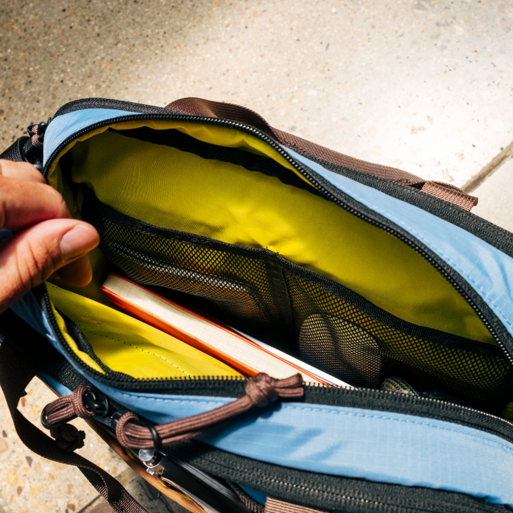 Open bag with yellow interior, holding notebooks and other items.