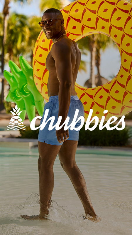 A man in swim shorts walking in water near a pool float.