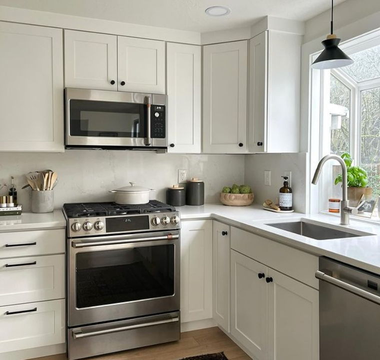 Modern kitchen with stainless steel appliances and natural light from a window.