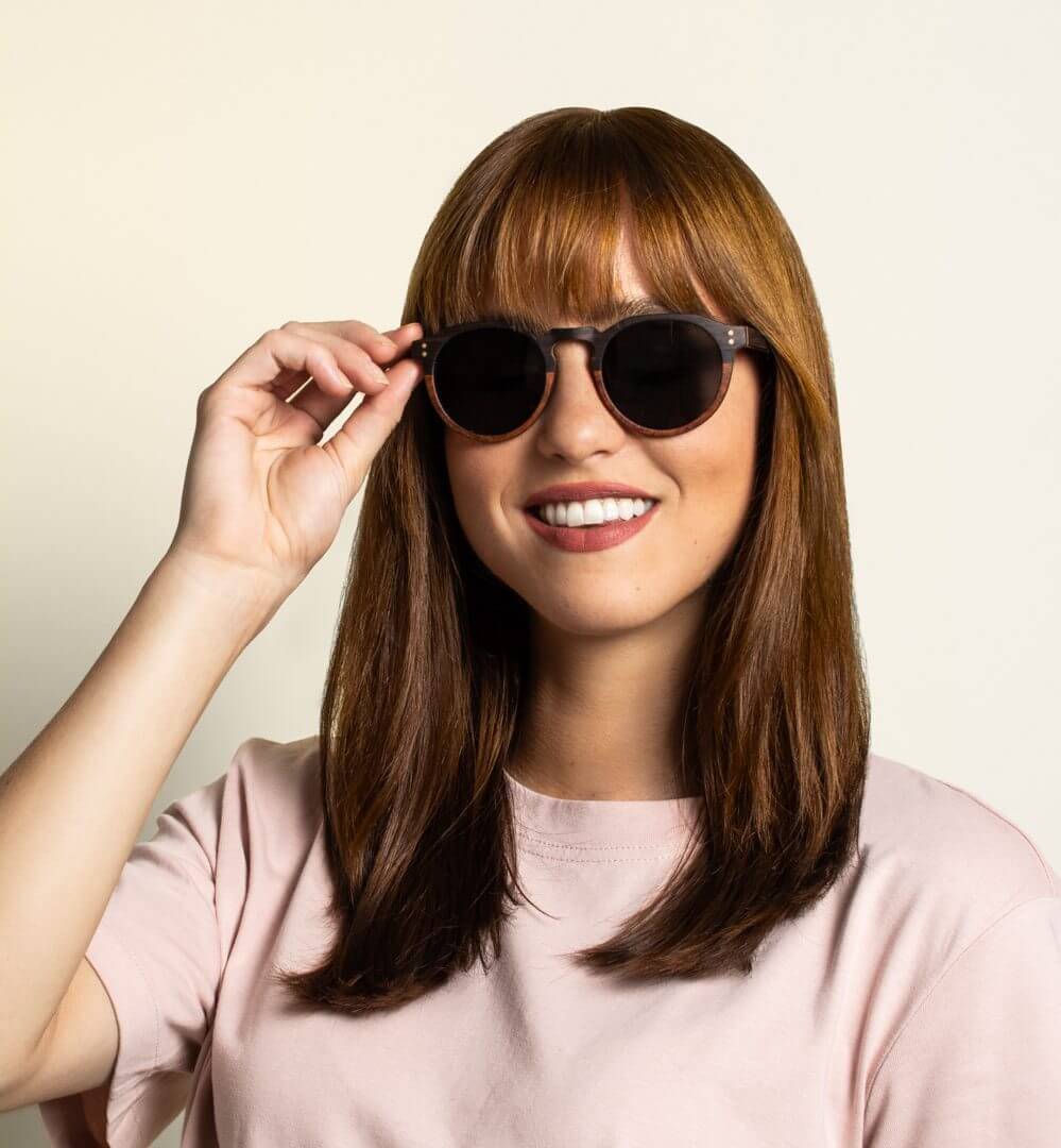 Femme avec petit visage portant Kraywoods Roseland, lunettes de soleil rondes à trou de serrure en ébène et bois de rose avec protection UV à 100 %, verres polarisés