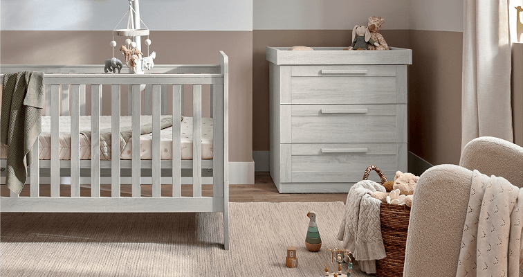 A cozy nursery with a crib, dresser, and soft decor elements.