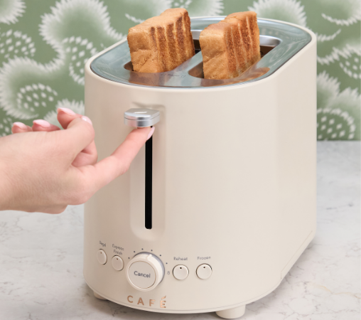 A hand pressing the lever of a toaster with two slices of bread.