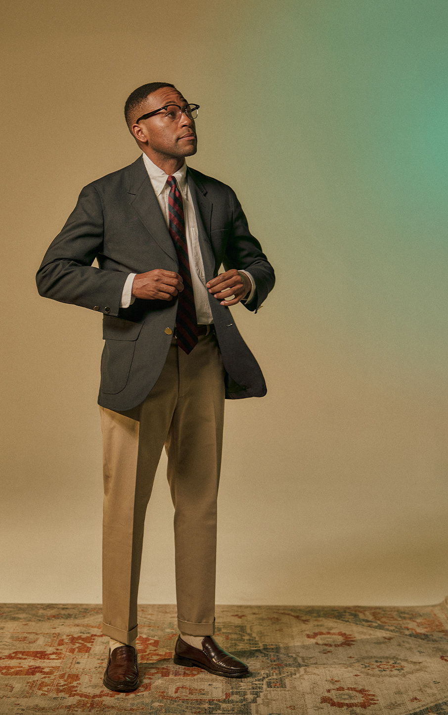 A man in a suit adjusting his jacket against a neutral background.
