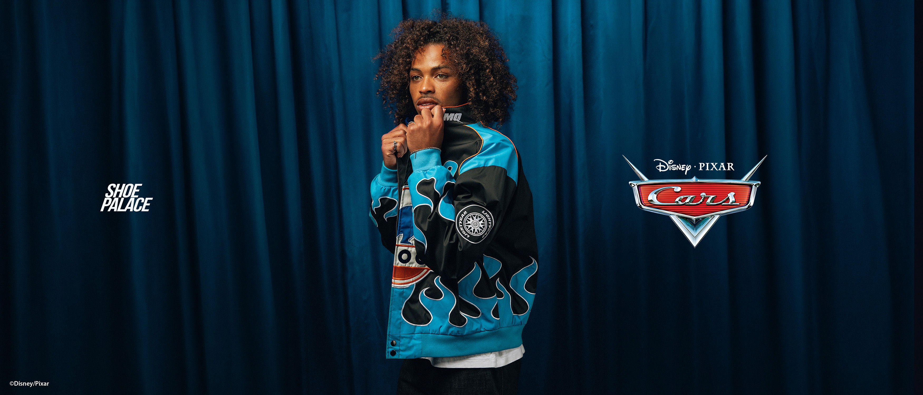 Person in a blue sweater with a graphic design, smiling against a backdrop.