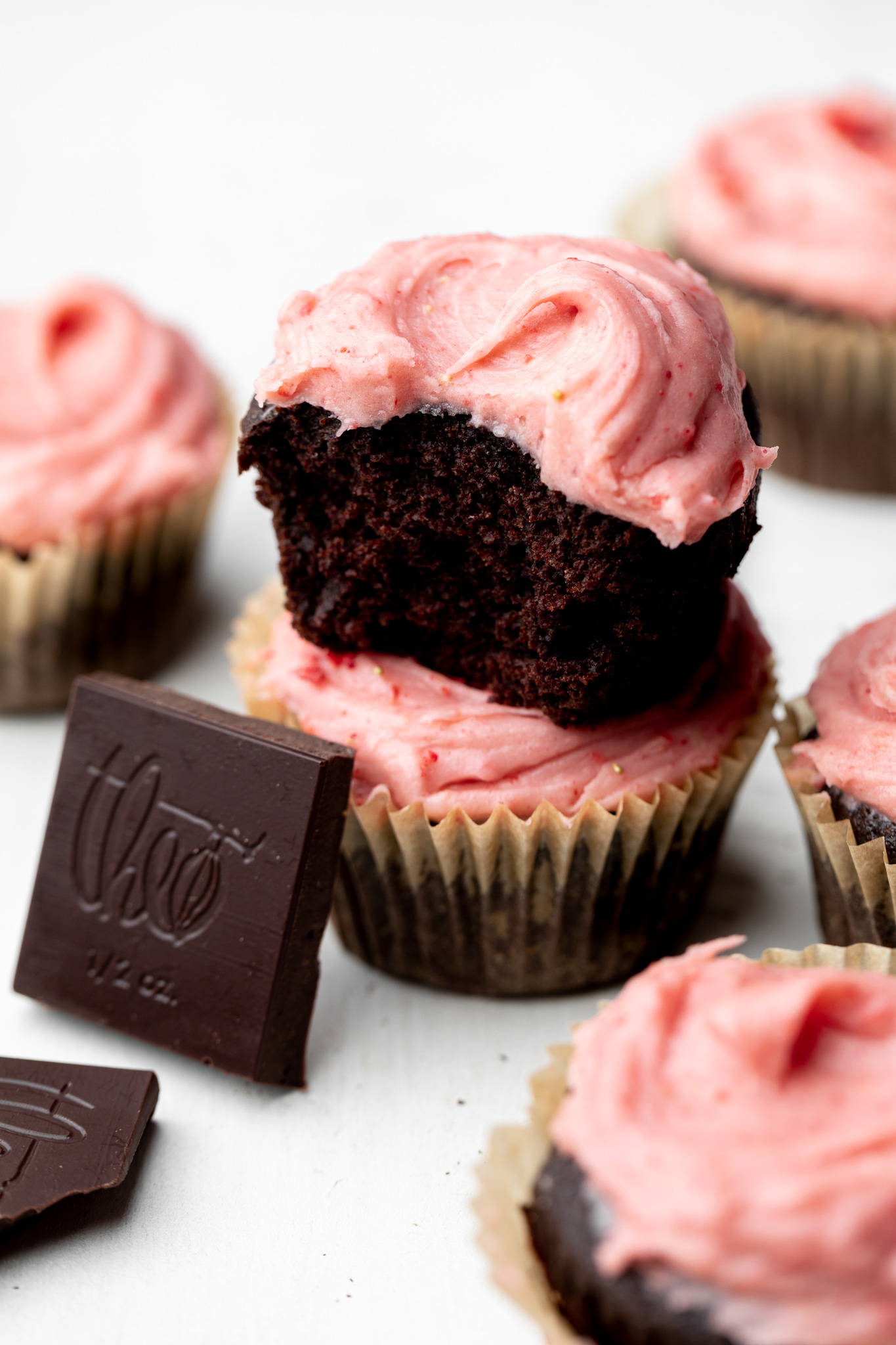 Half of a chocolate cupcake stacked on  a full one with a baking bar square.