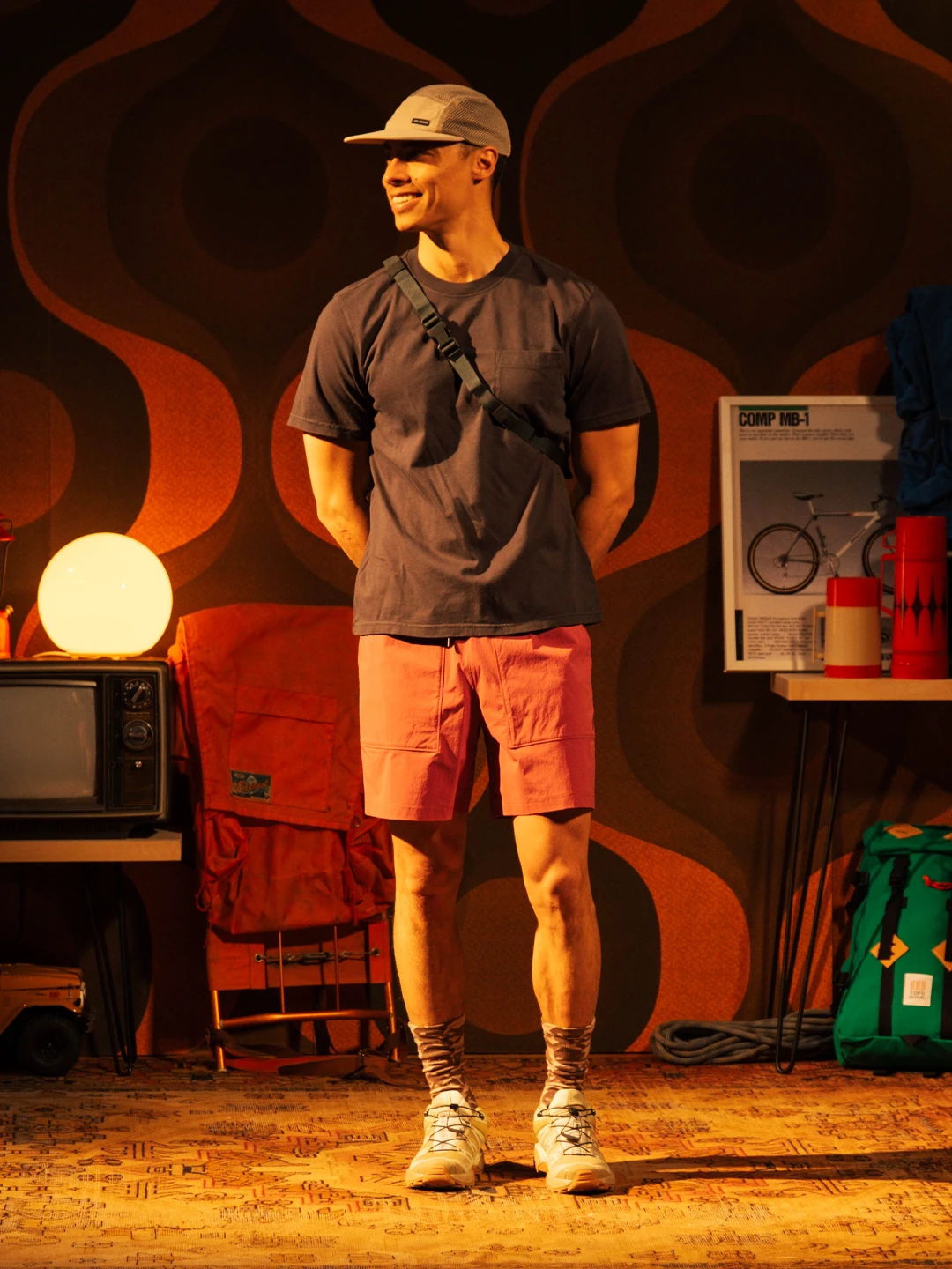 Person in casual attire standing in a retro-themed room with various objects.