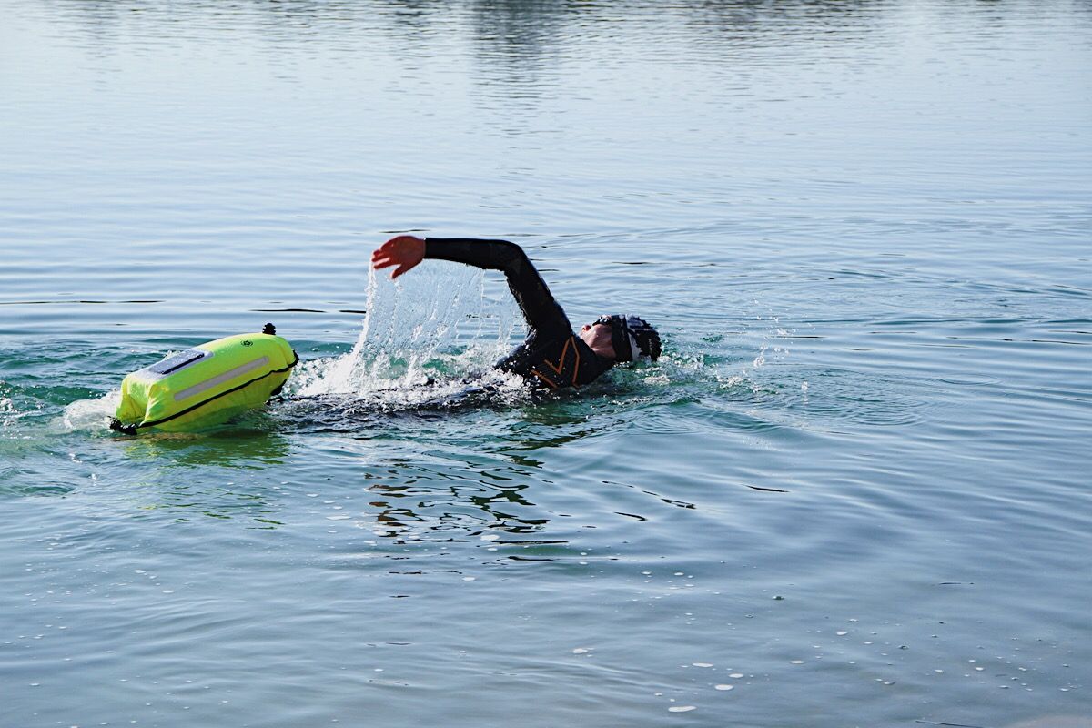 Ein Triathlet im Wasser mit einer gelben Schwimmboje.