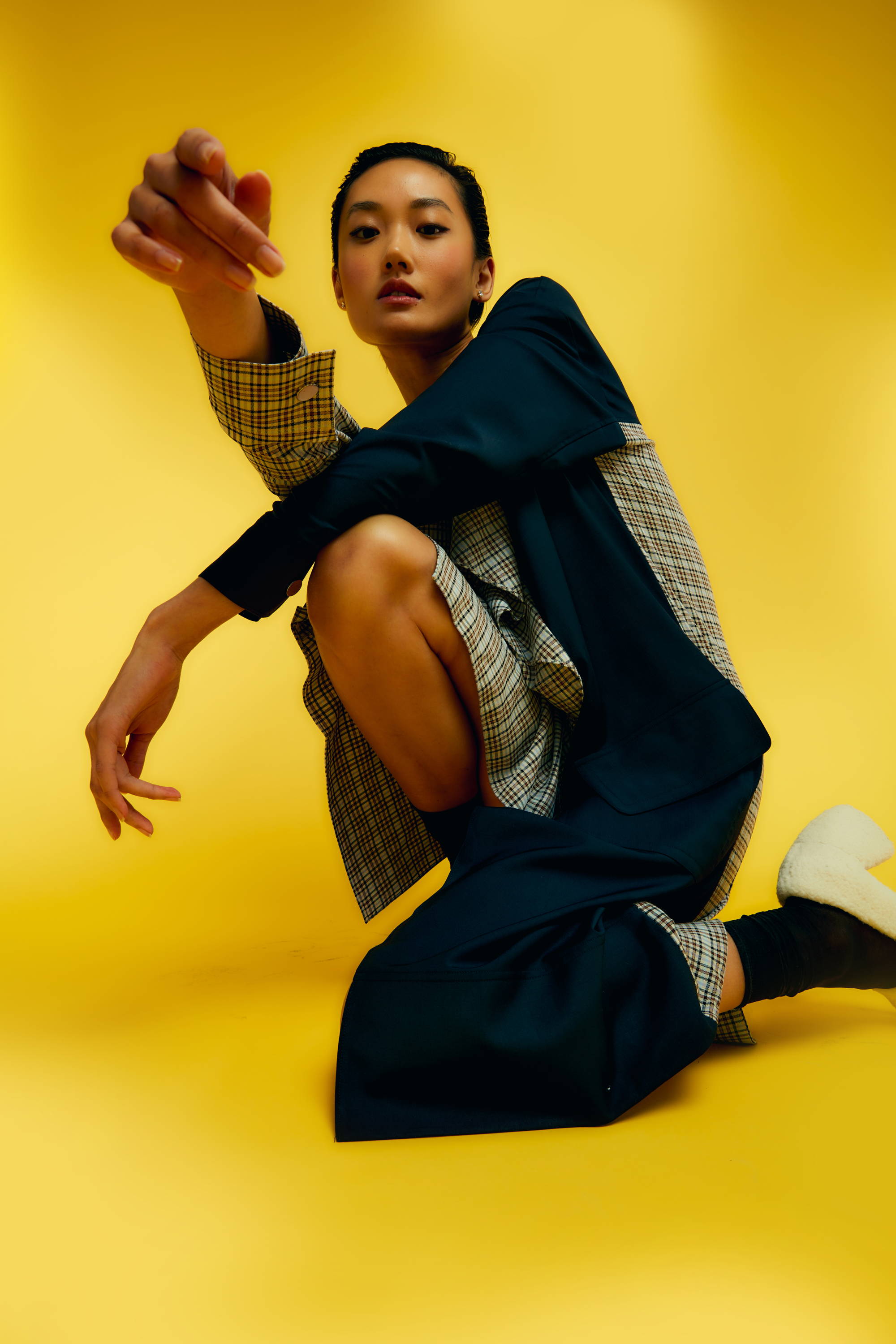 A person in stylish clothing poses against a yellow background.