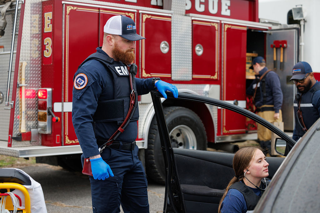 Emergency responders assisting a person at a vehicle accident scene.