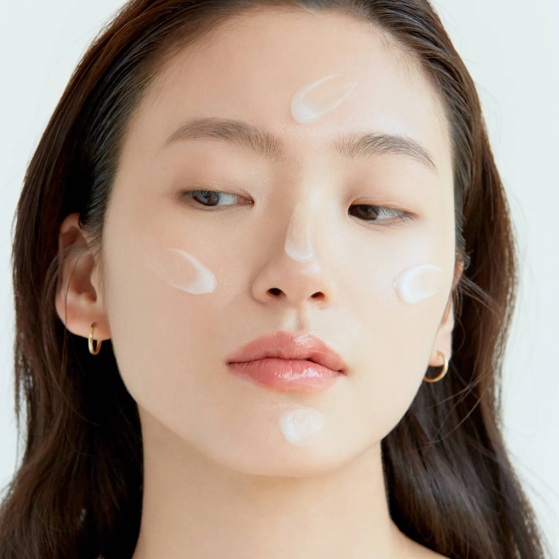 Girl using moisturizer on her cheeks, forehead, nose and chin