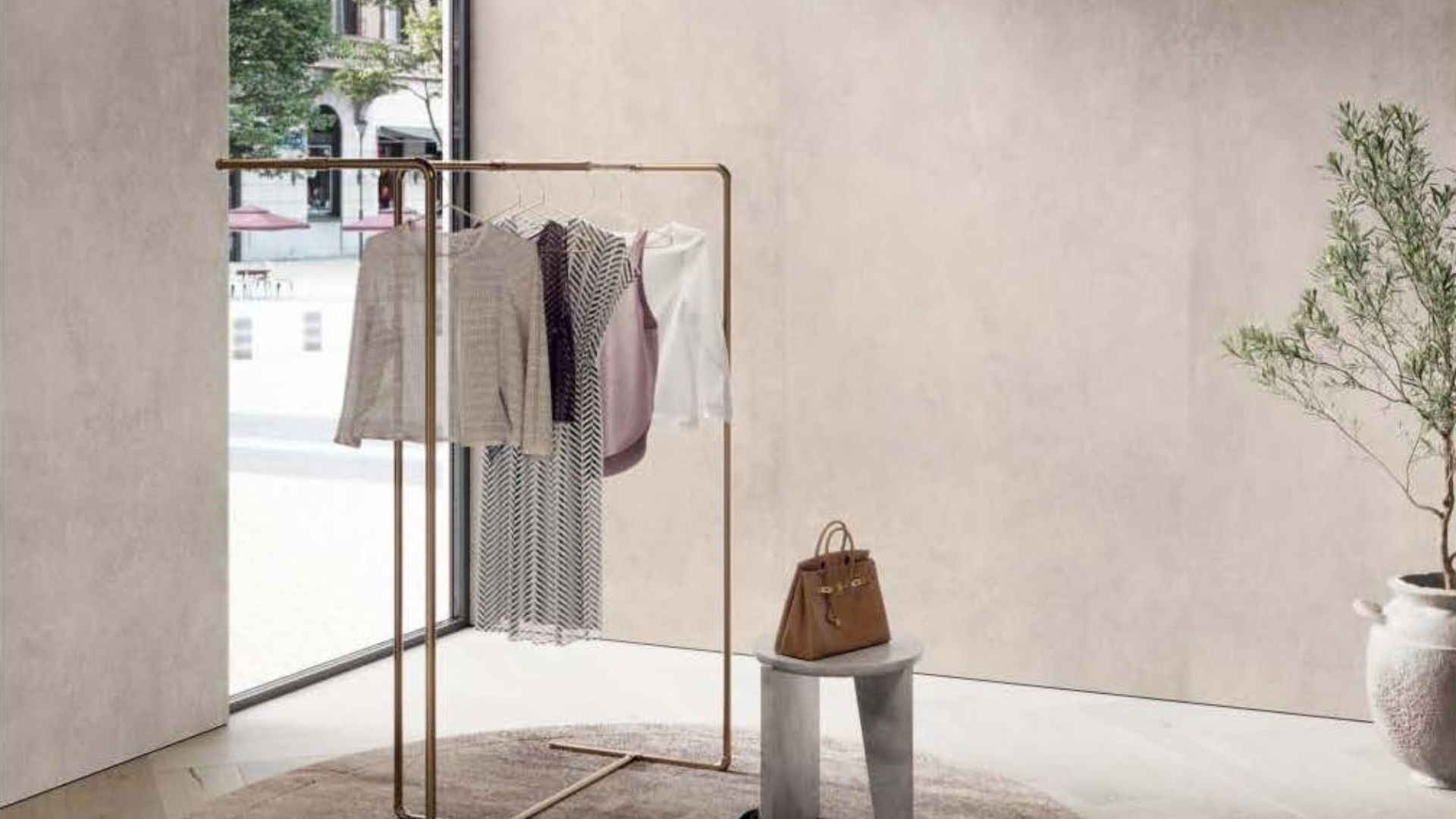 Large format Alluslate panels in a retail setting with clothing rack and garments, a bag, and a plant in a minimalist setting.
