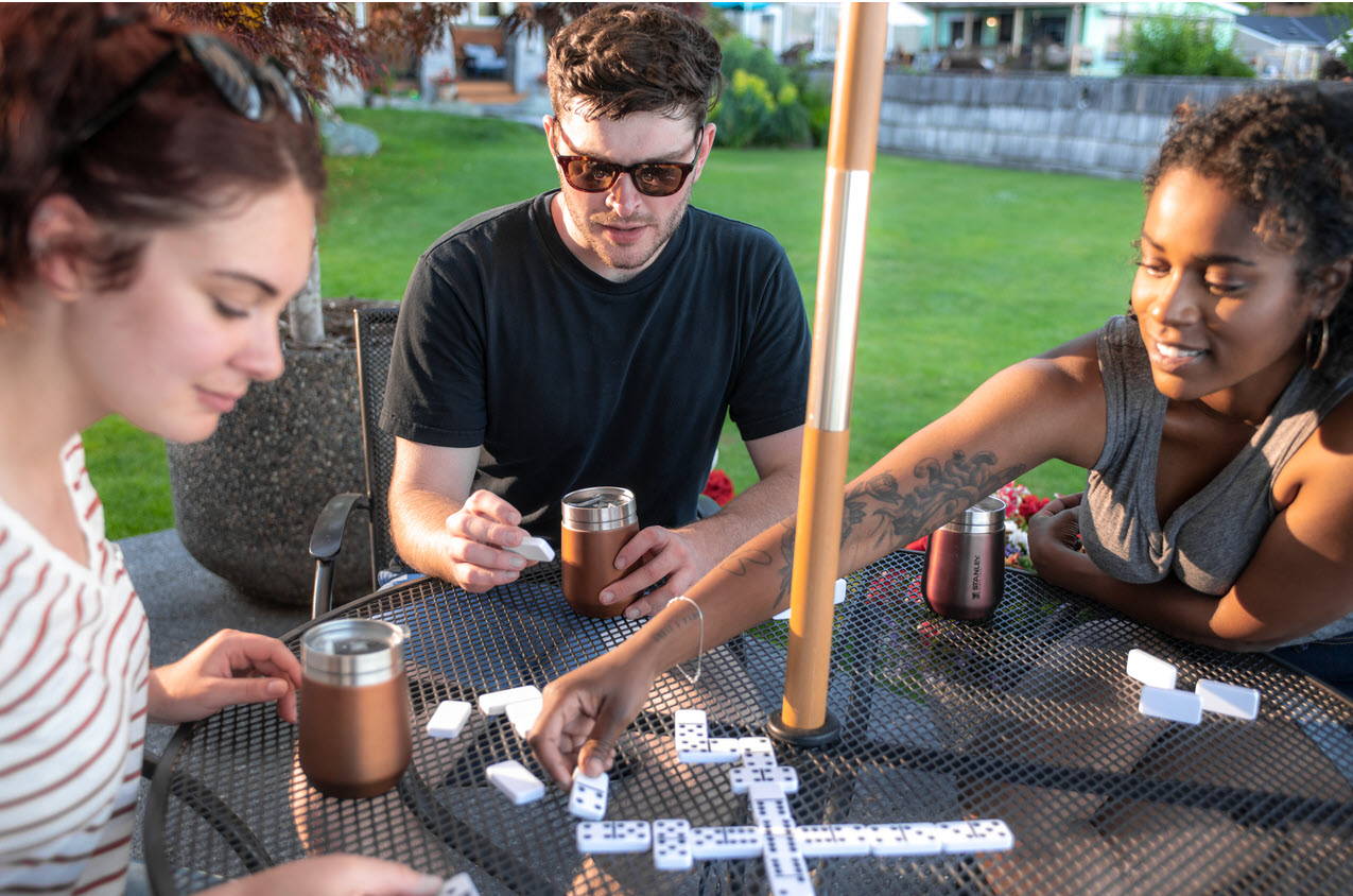 Friends at an outdoor table playing dominos with Stanley wine tumblers