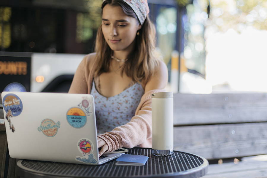 Girl on laptop with cofee tumbler