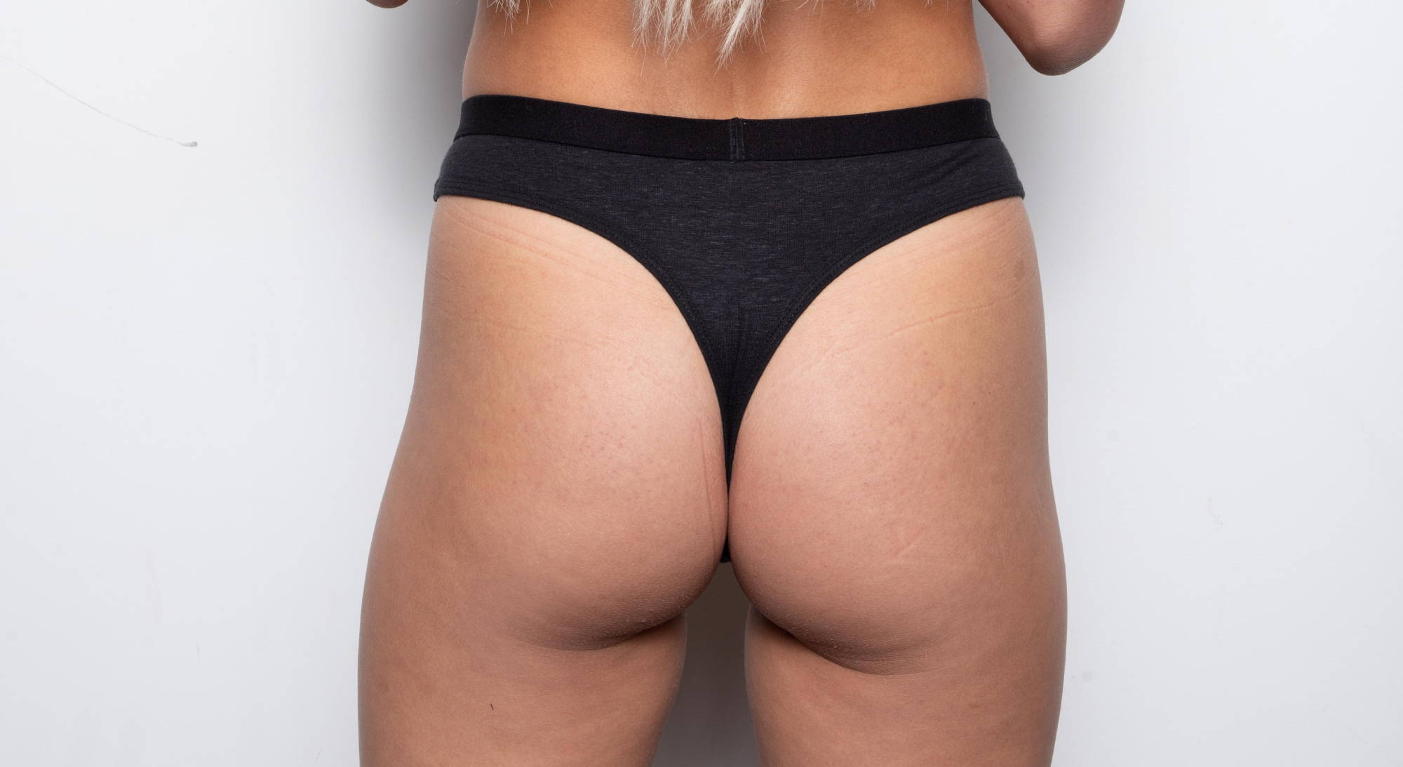 a woman’s butt in a black thong with her blonde hair reaching to her waist