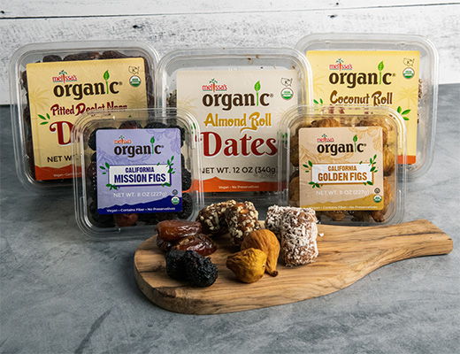 Assorted organic snacks including dates and energy balls on a wooden board.