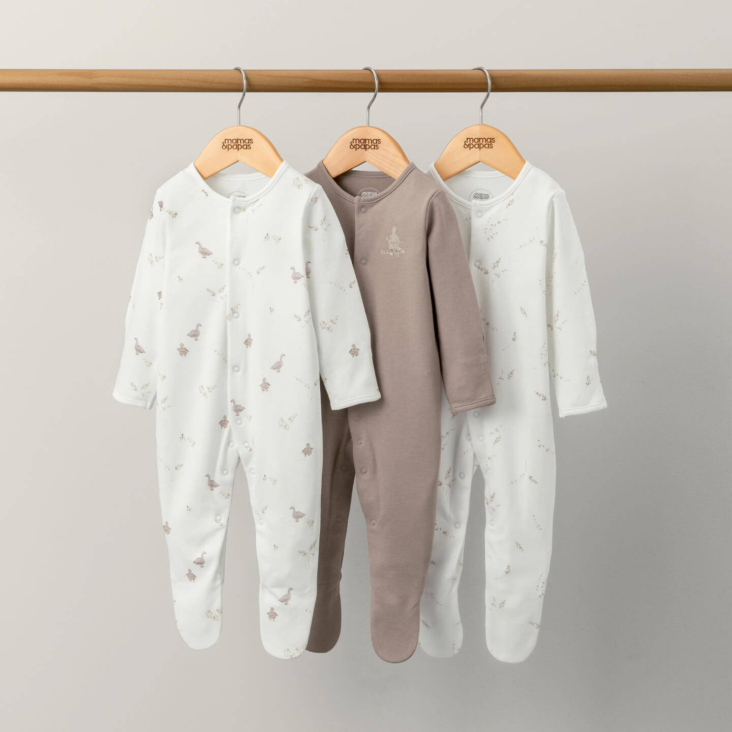 Three neutral baby grows hung up