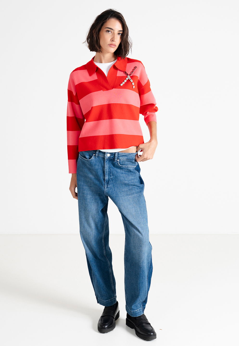 Person wearing a red striped shirt and blue jeans, standing against a white background.