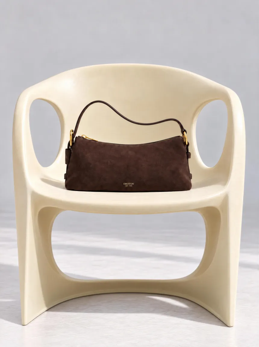 A brown handbag on a white modern chair.