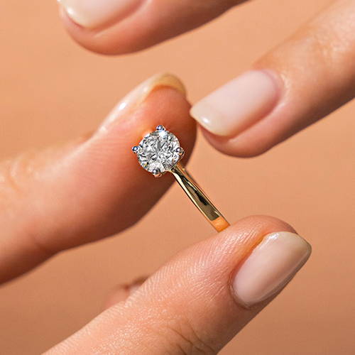 women placing a solitaire engagement ring with a lab grown diamond on her finger 
