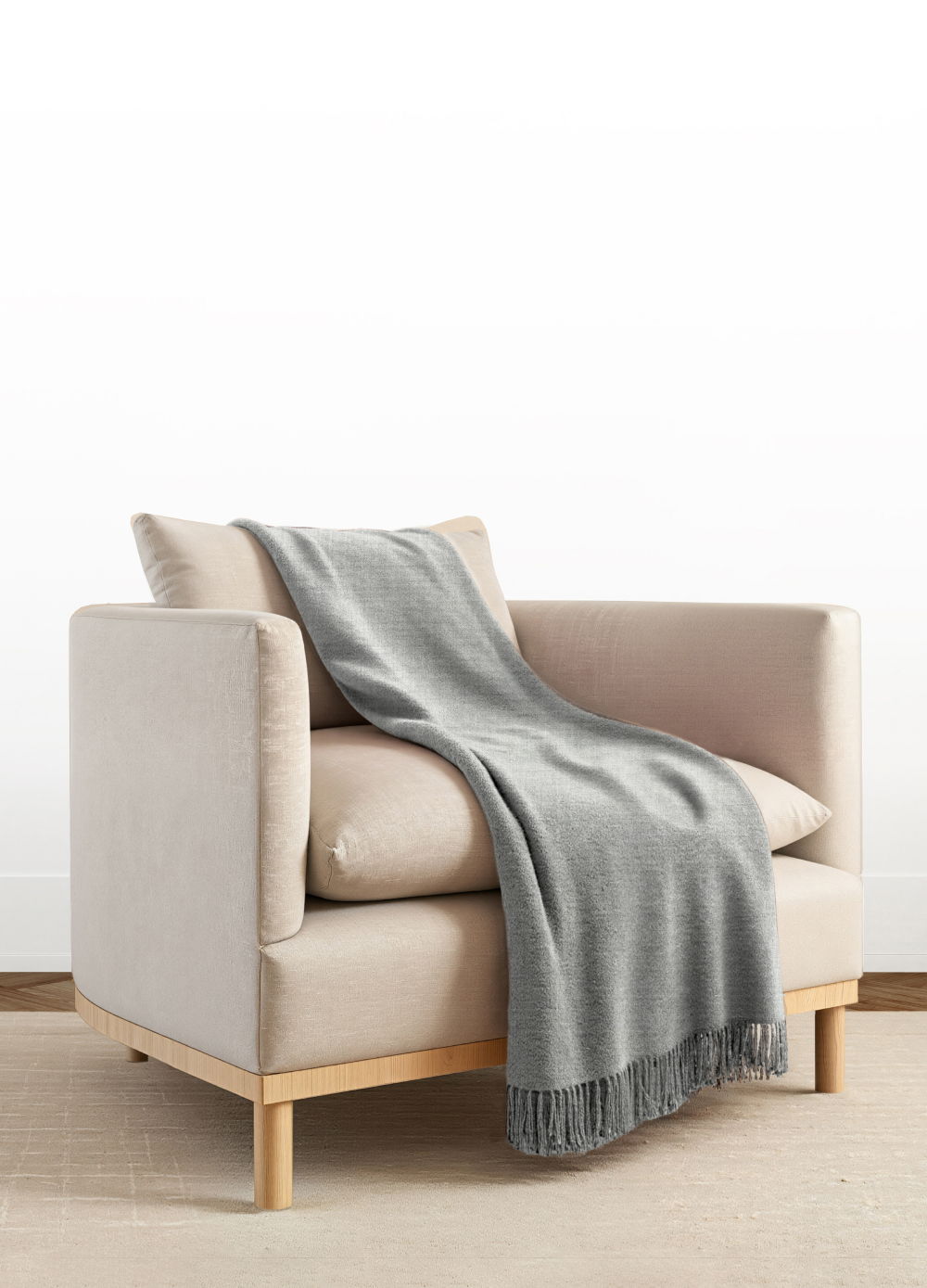 A cozy armchair with a gray blanket draped over it.