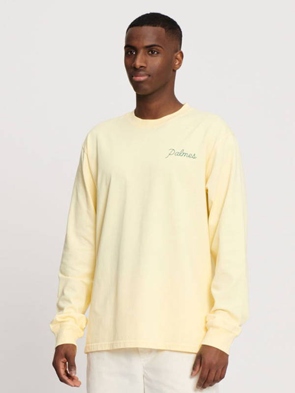 A model wearing the Palmes Sunset long sleeve t shirt in Sunfaded Yellow showing the small chest logo.