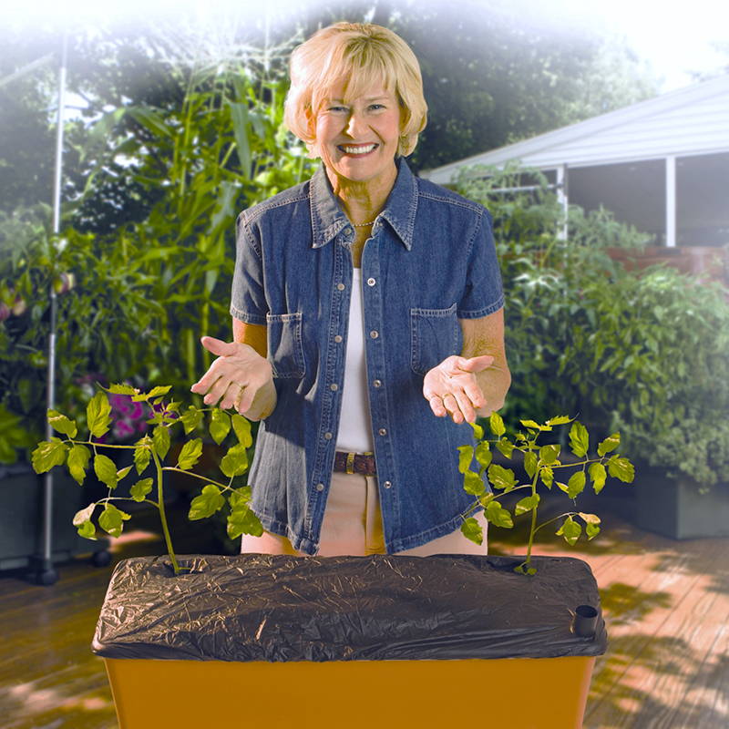 Woman showing off a correctly installed EarthBox black mulch cover with 2 holes cut for her plants