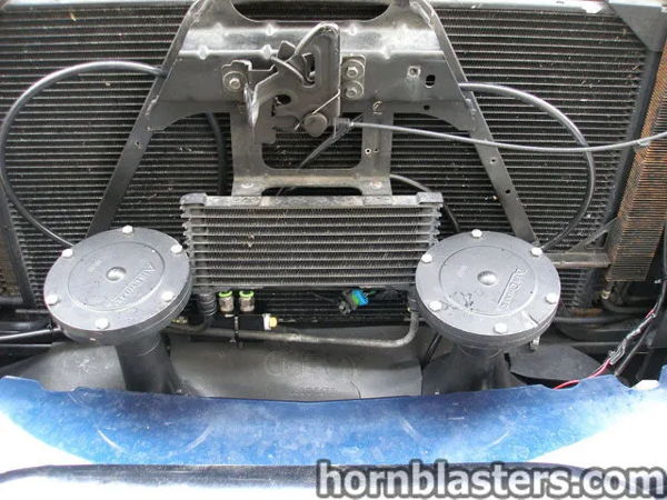 Front view of the horn components mounted behind the grille on Jerry's 2006 Chevrolet Silverado 1500 Extended Cab, install photo 9