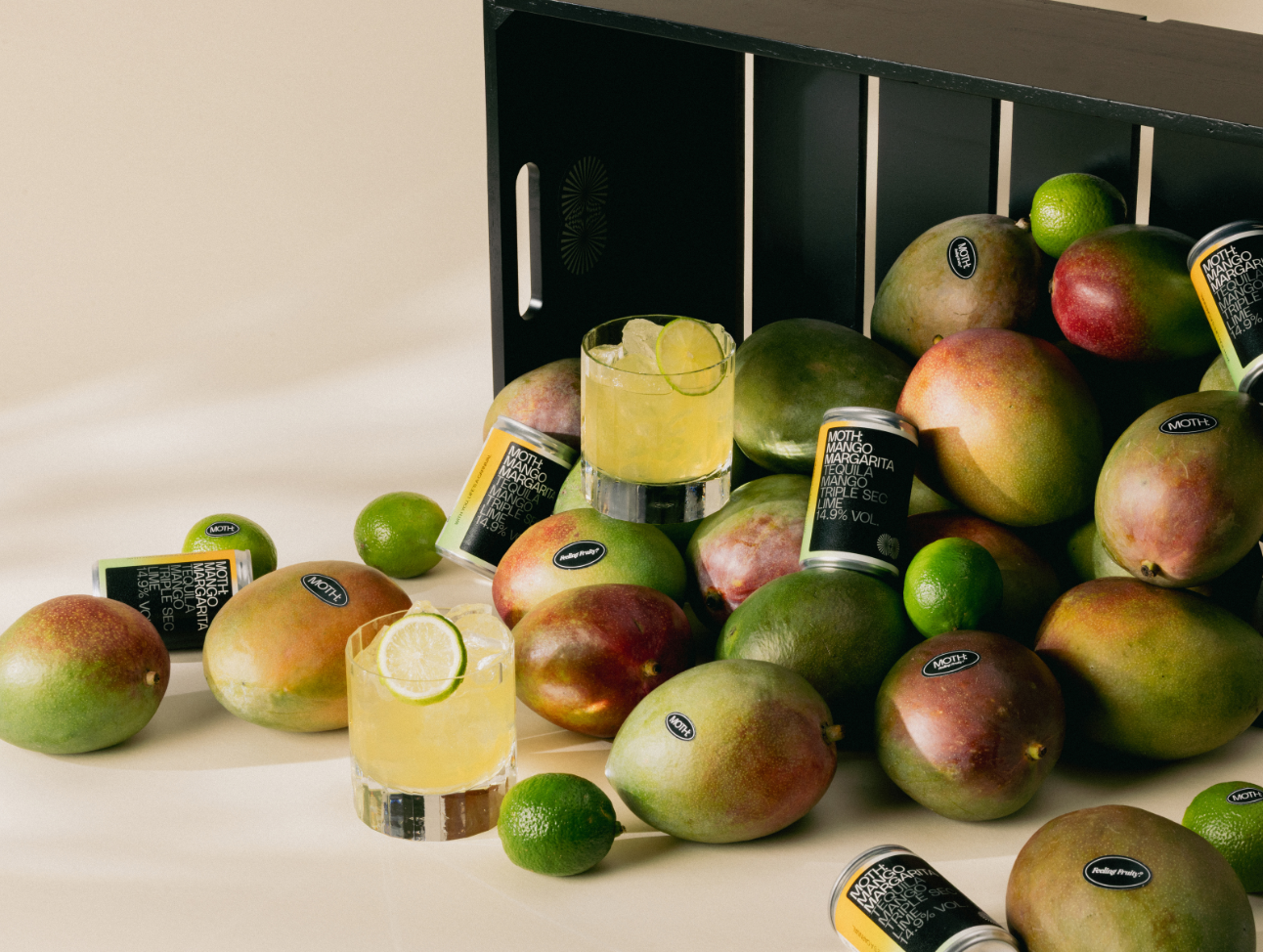 Mangoes, limes, and cocktails scattered around a black crate.