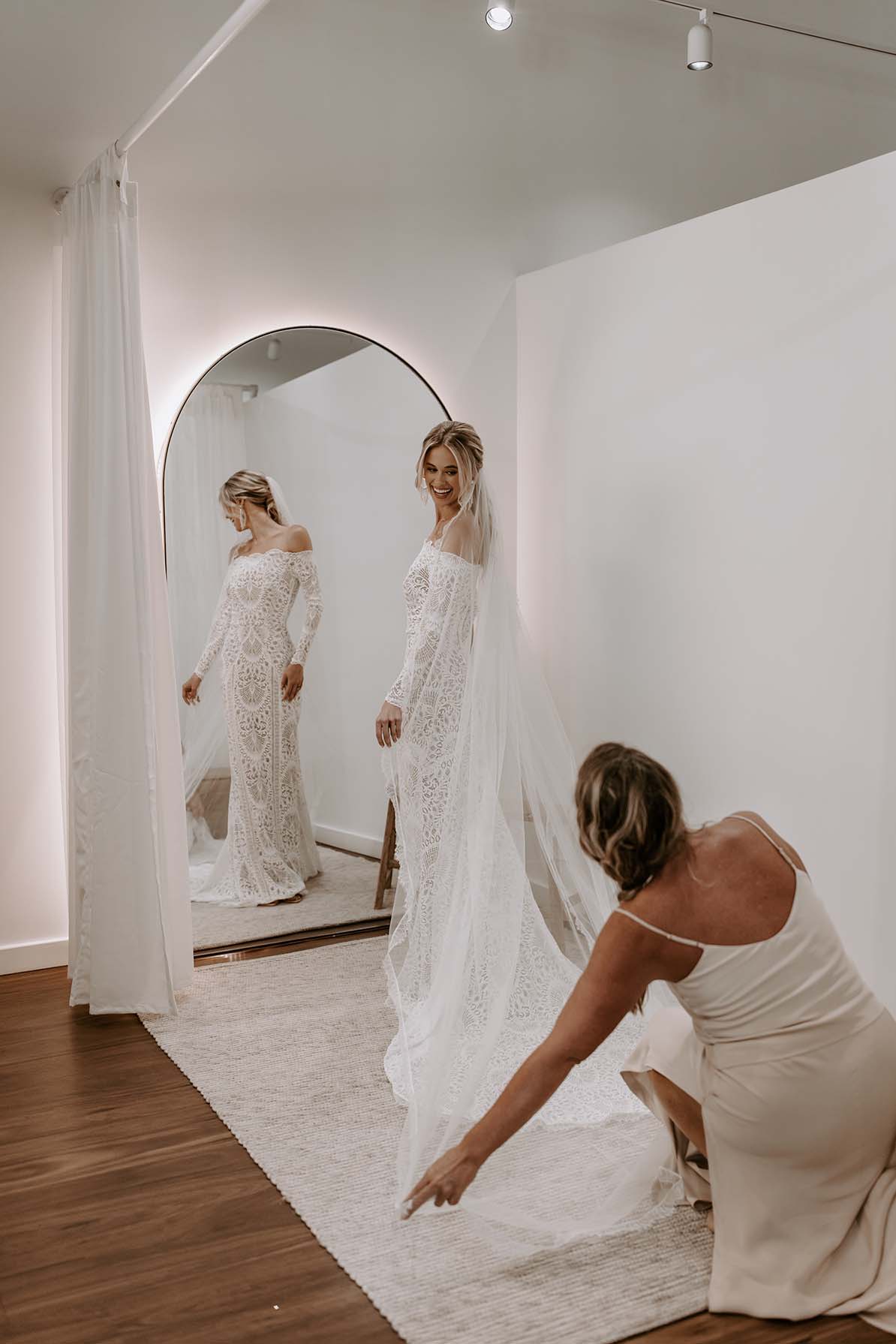 Stylist helping Bride with veil in Grace Loves Lace Showroom