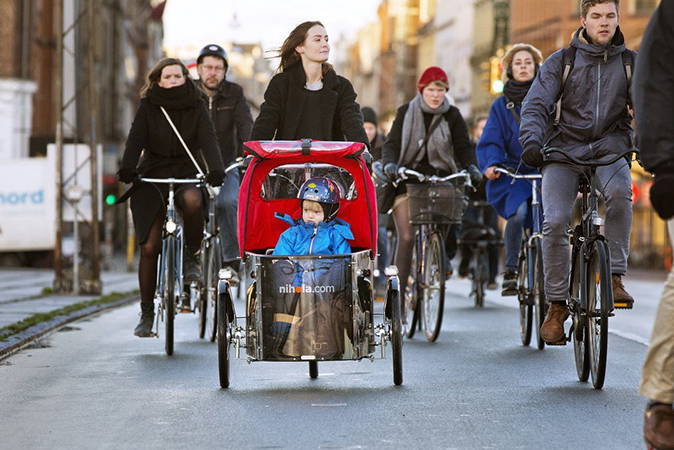 A woman rides a Nihola in rush-hour bike traffic in Copenhagen. Her young son rides in the cargo box up front.