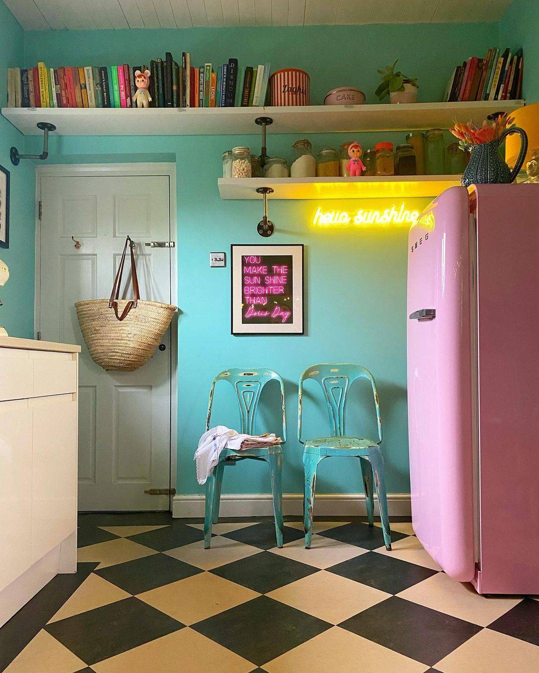 A colourful kitchen with a yellow hello sunshine neon light hung on a blue wall.